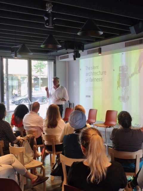 Daniel Glinz opening the Trustworthy AI Circle in front of a projected slide reading “The silent architecture of fairness”, with a seated audience.