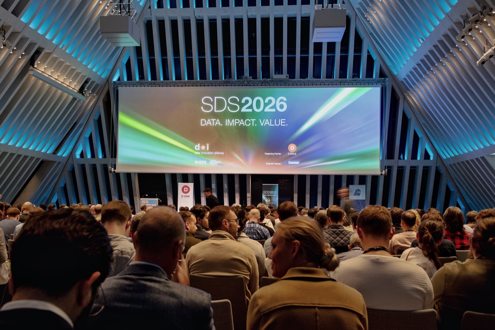 The full audience before the main stage screen at the 2026 IEEE Swiss Conference on Data Science and AI.